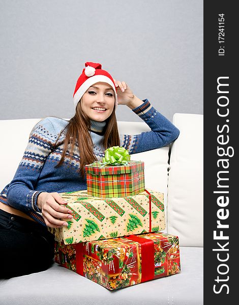 Pretty smiling caucasian girl in santa hat with gifts