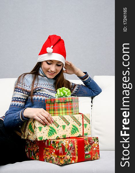 Pretty caucasian girl in santa hat looking at gifts