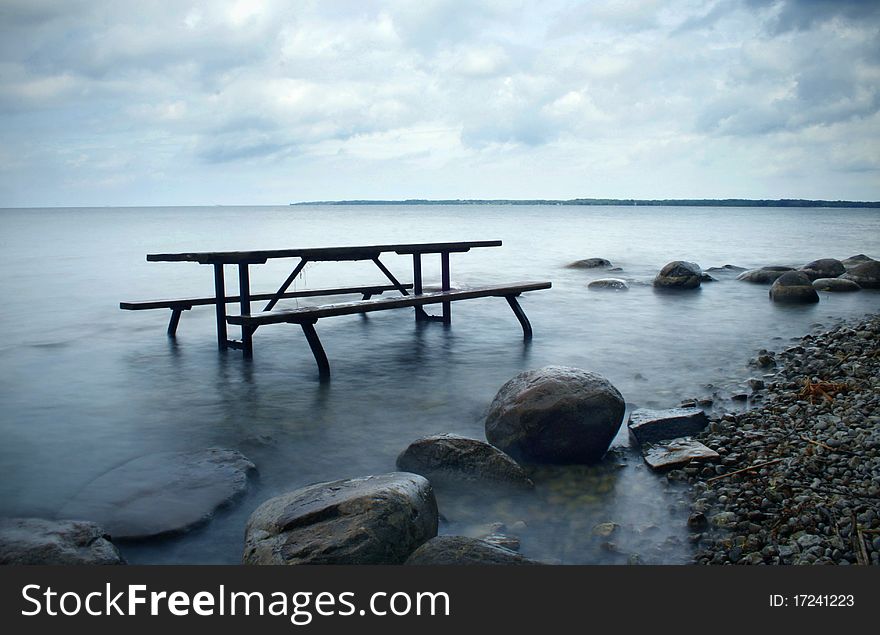 A picnic table half submerged in the lake. A picnic table half submerged in the lake.