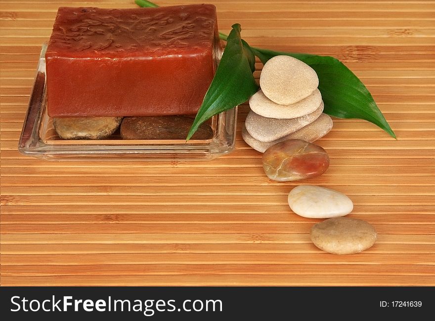 Spa scene of natural soap, stones and leaf on bamboo