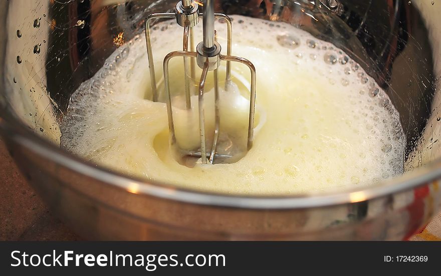 Cooking Beaten Eggs with Mixer Whisks in metal Bowl closeup. Cooking Beaten Eggs with Mixer Whisks in metal Bowl closeup.