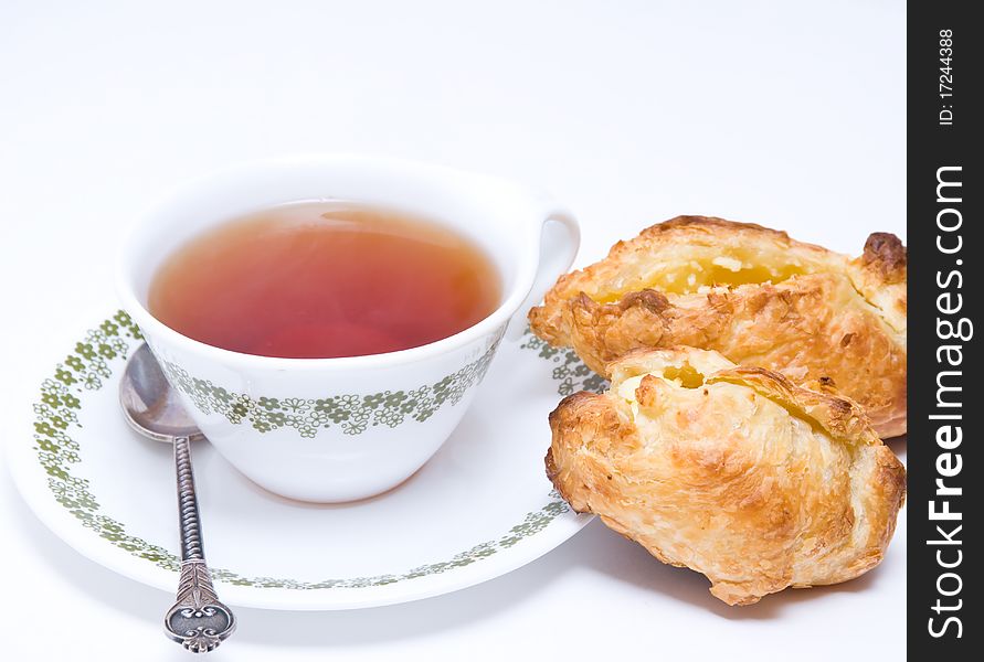 Pies of flaky pastry with cream cheese and cap of tea on the white background. Pies of flaky pastry with cream cheese and cap of tea on the white background