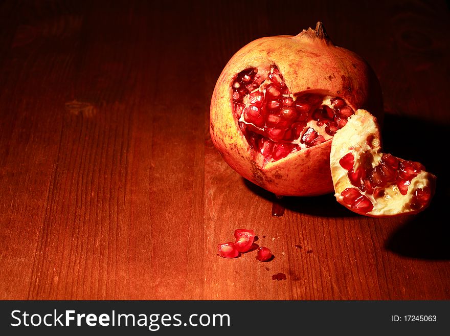 Fresh pomegranate lying on dark wooden background with lighting effect. Fresh pomegranate lying on dark wooden background with lighting effect