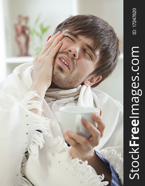 Young man with headache or toothache on the sofa. Young man with headache or toothache on the sofa