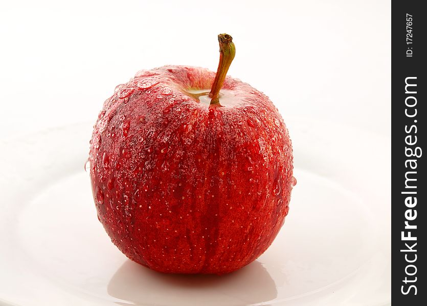 Red apple on white plate, towards white background