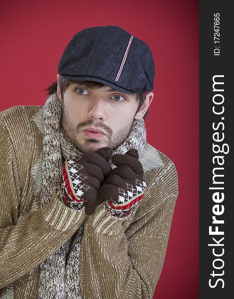 Freezing man in cap and sweater over red background