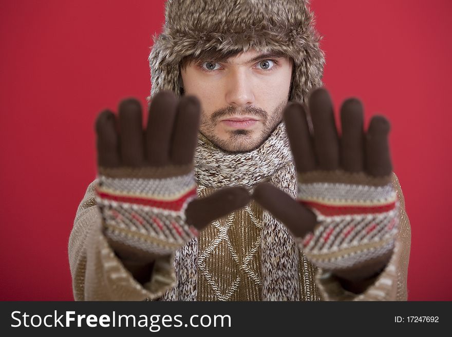 Man in winter clothing making stop hand gesture over red background