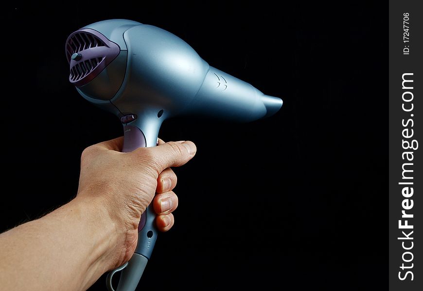 Silver colored hairdryer held by hand, towards black