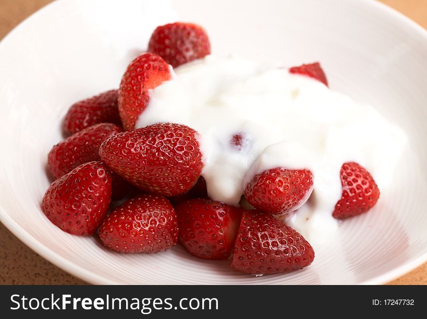 Sliced fresh strawberries with cream in a white plate. Sliced fresh strawberries with cream in a white plate