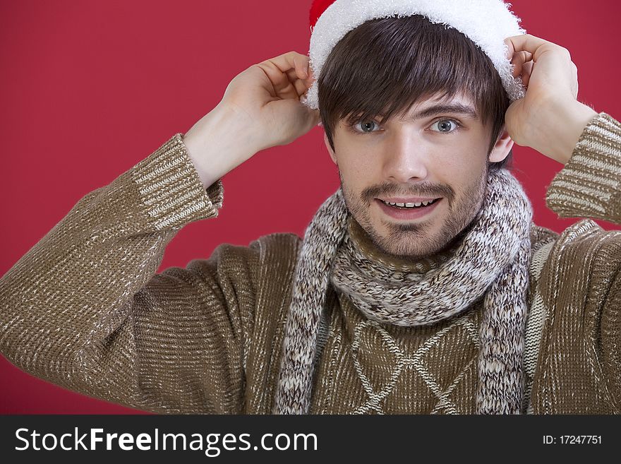 Young happy man in santa hat over red background