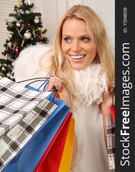 Sexy blond angel standing in front of a christmas tree with some shopping bags. Sexy blond angel standing in front of a christmas tree with some shopping bags