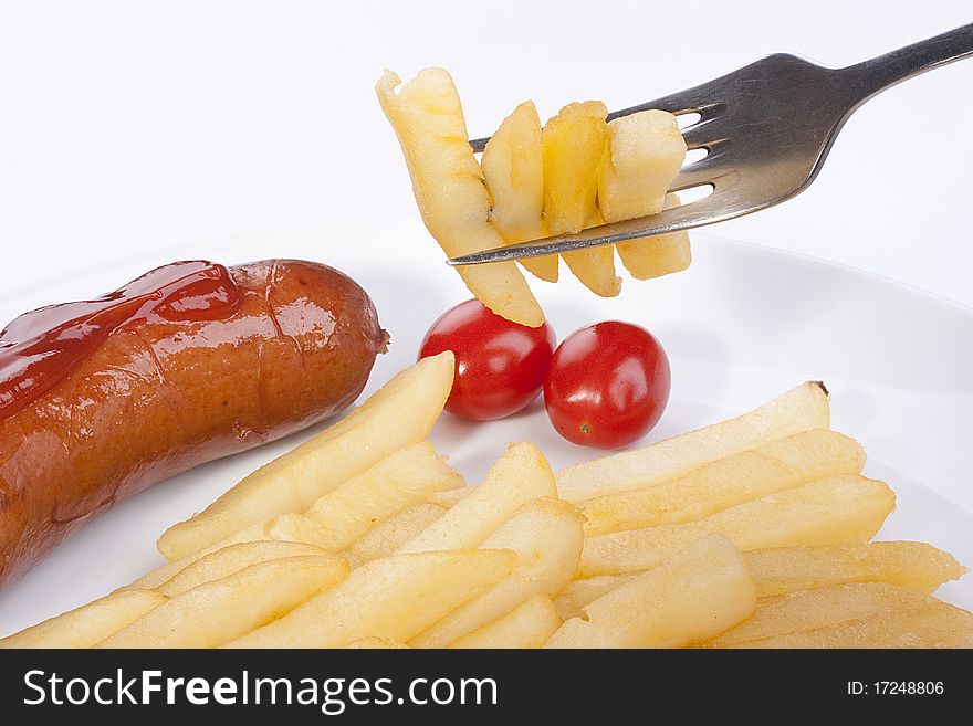 Fried potato on a fork, in a plate tomatoes and sausage.