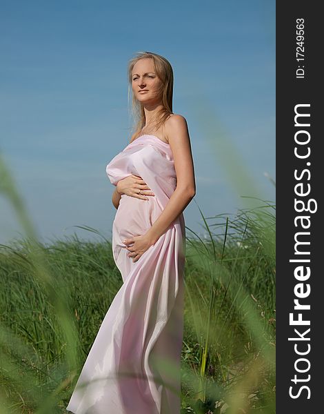Beautiful pregnant with pink fabric fluttering in the wind. Beautiful pregnant with pink fabric fluttering in the wind