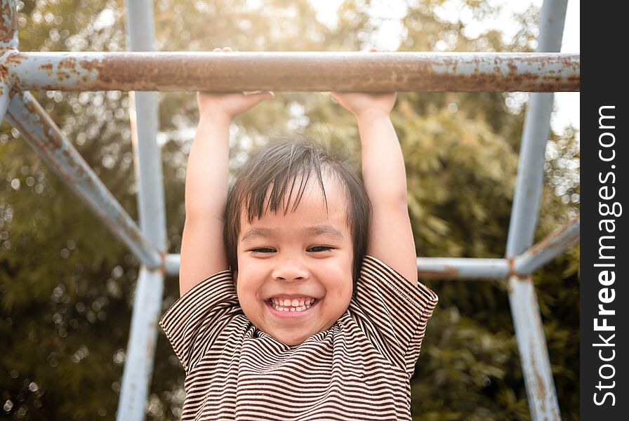 Cute Asian Little Girl Hanging The Monkey Bars By Her Hand To Exercise At Out Door Playground On Sunny Day