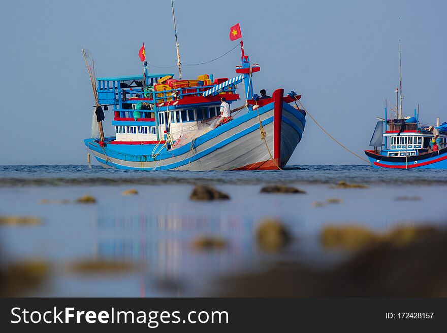 Bright fishing boat in the roadstead in the morning at low tide