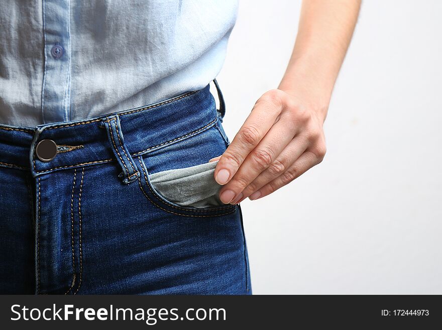 Woman showing empty pocket on light background