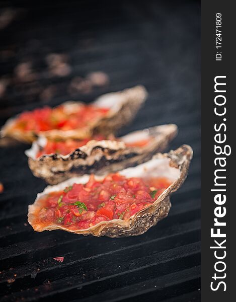 Oysters on the grill. Oysters with tomato sauce. Street food.Selective focus