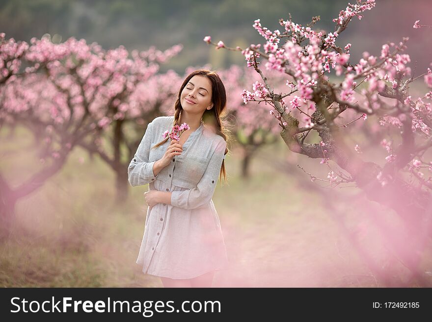 A girl with closed eyes in the park. Beautiful young woman near the blossoming spring tree