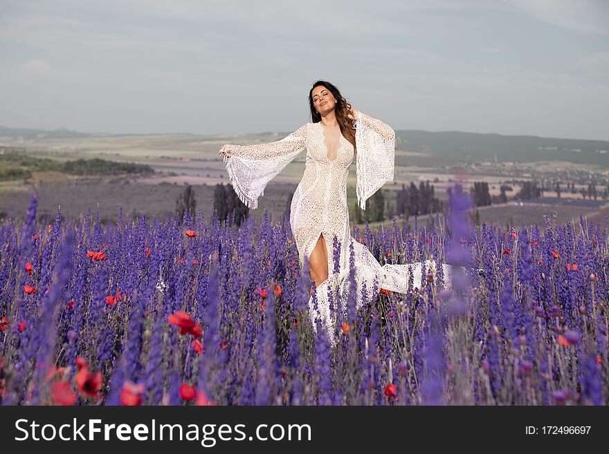 A woman whirls and dances in a field with lavender. Bride in white dress in lilac field with lavender