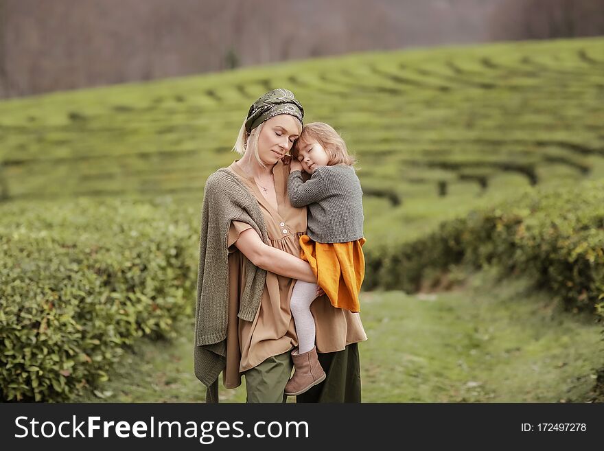 Mom Cuddles Baby Outdoors. A women with a child walking on a tea plantation