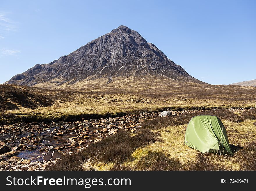 Pitched tent in the wilderness next to Buachaille Etive MÃ²r in scotland during day