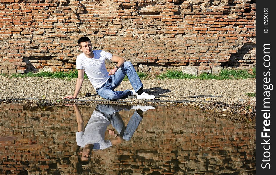 Portrait of an young man thinking, sitting near a lake. Portrait of an young man thinking, sitting near a lake