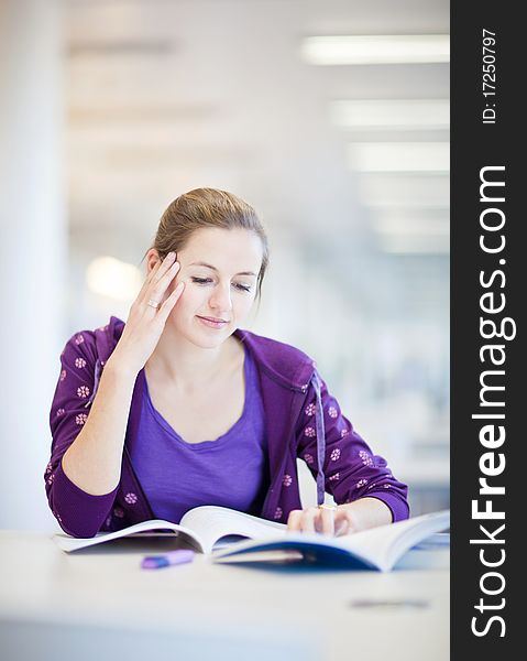 Pretty female college student in a library