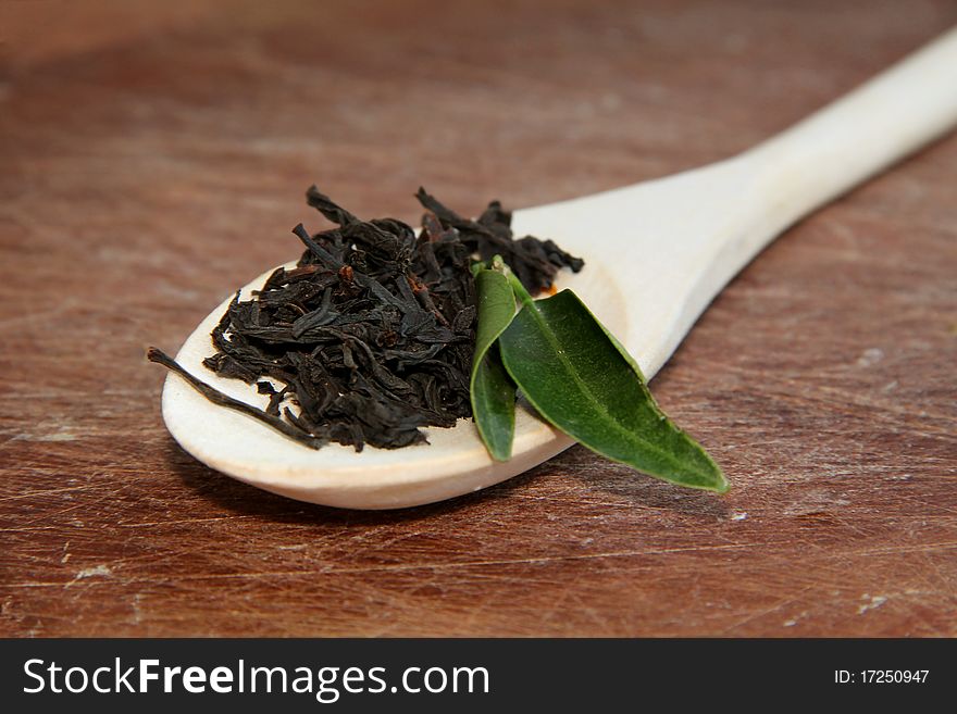 Black tea on spoon over a wooden texture. Black tea on spoon over a wooden texture