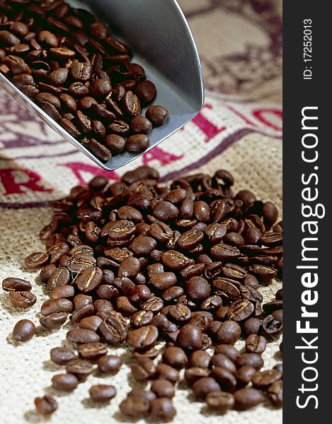 Roasted coffee beans on a spoon and table.