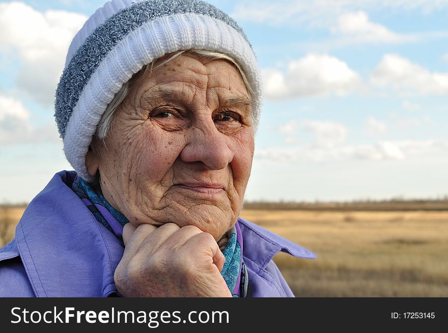 Reflecting, an elderly woman looks away, the background road, autumn