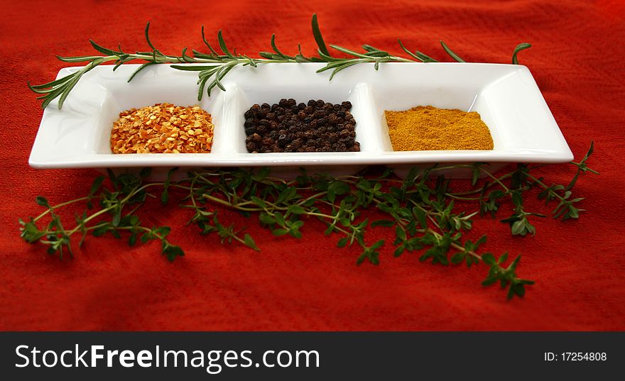 Fresh and dried herbs and spices in white dish on red background. Fresh and dried herbs and spices in white dish on red background