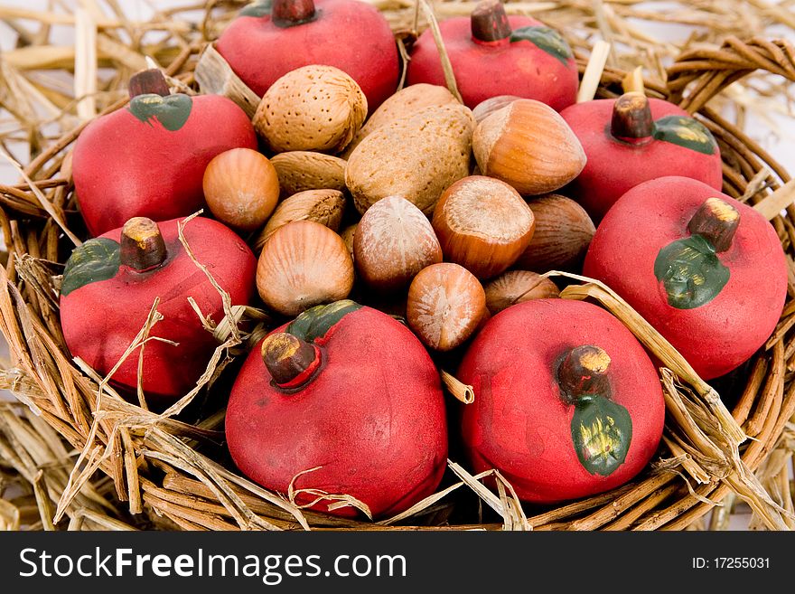Closeup of red apples made of clay and nuts in a basket with straw. Closeup of red apples made of clay and nuts in a basket with straw