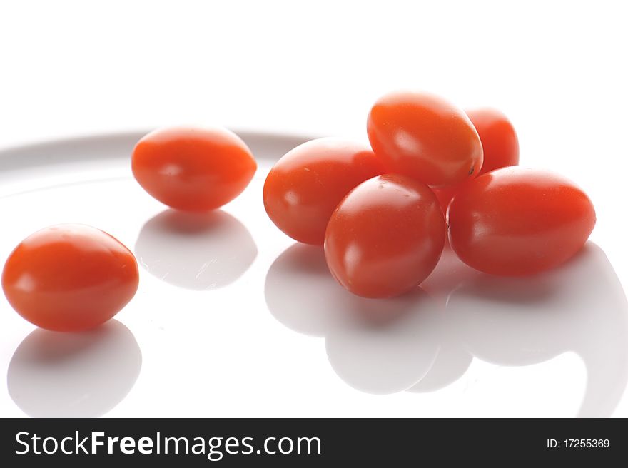 Photo of small red tomtoes on the white plate. Photo of small red tomtoes on the white plate