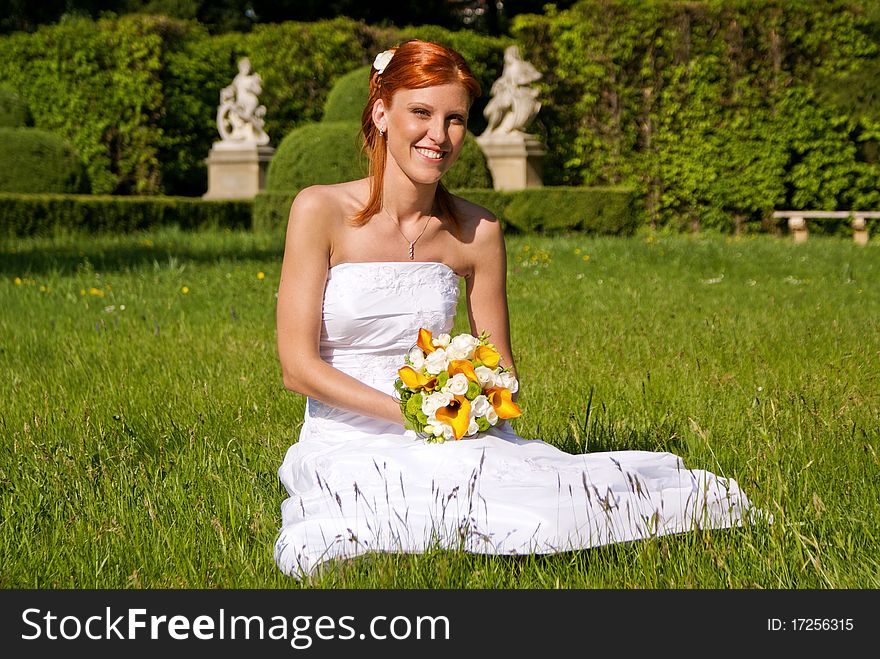 Portrait of young bride at the garden sitting on grass. Portrait of young bride at the garden sitting on grass.