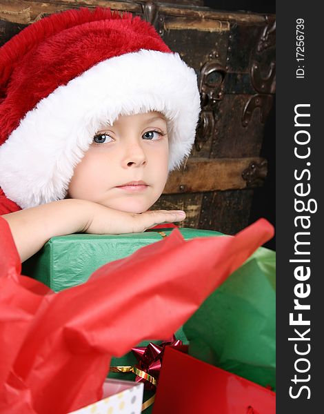 Beautiful boy wearing a christmas hat waiting to open presents. Beautiful boy wearing a christmas hat waiting to open presents