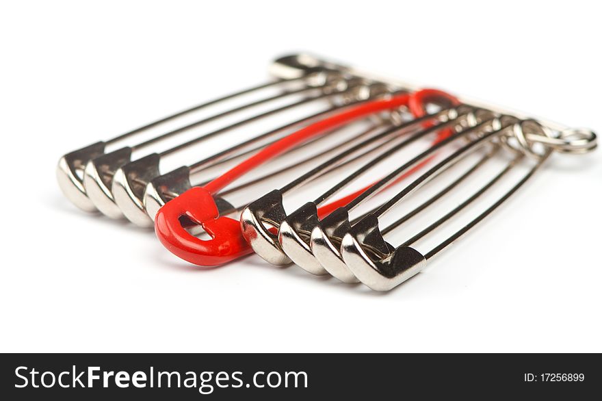 Safety pins in a row with one distinguishing red pin. Safety pins in a row with one distinguishing red pin