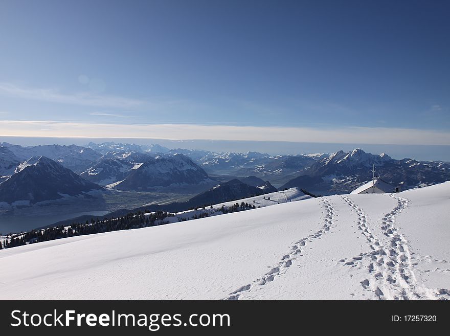 Footprints in the snow with blue sky and mont Rigi