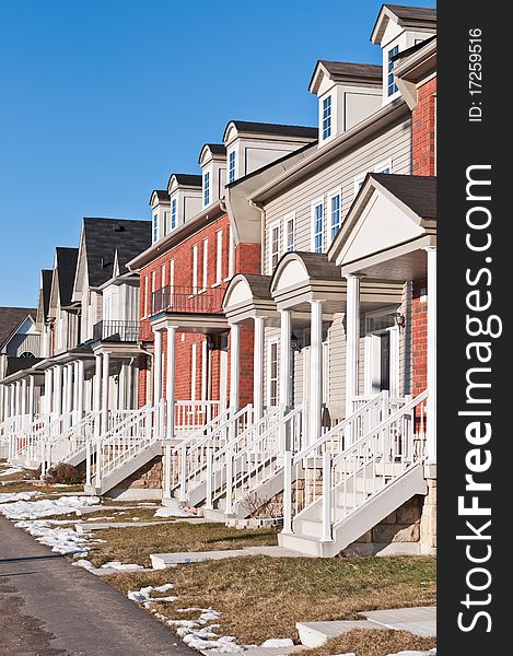 A row of recently built townhouses on a suburban street in winter.