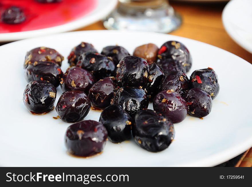 Black ripe olives on a white plate on table. Black ripe olives on a white plate on table