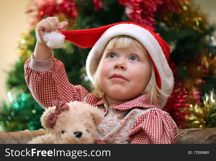 Small girl with toy near christmas tree on the background