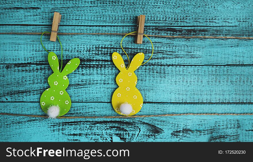 Easter holidays concept, green and yellow bunny toy on trendy blue wooden background, copy space