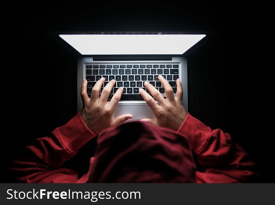 Hooded hacker hand stealing data from laptop .