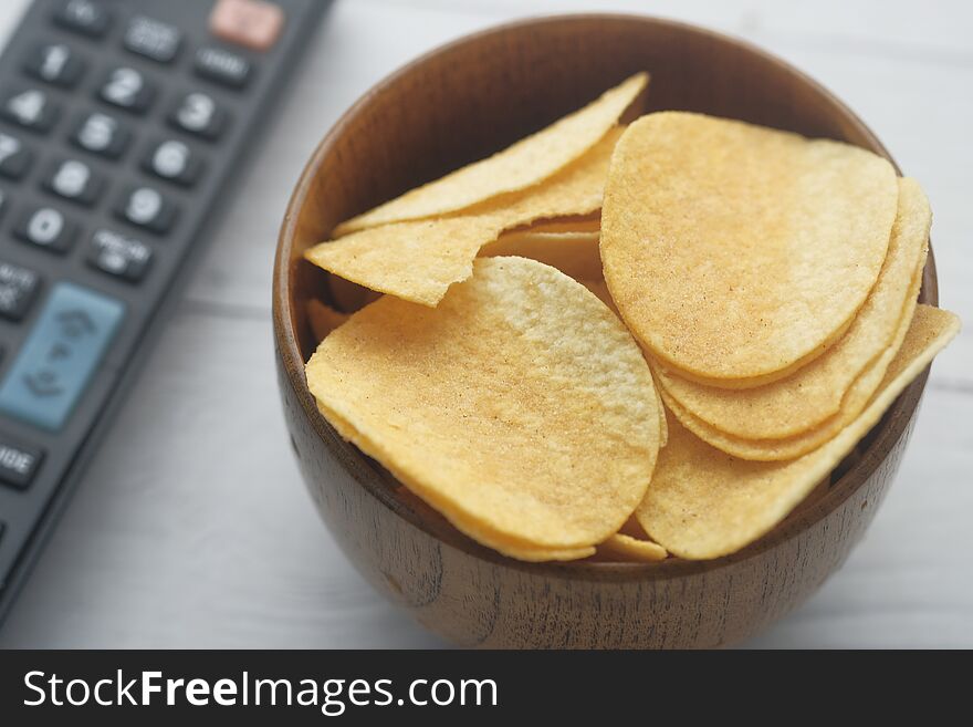 Close up of chips in a bowl with tv remote .