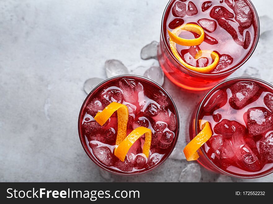 Fresh Negroni cocktails with orange zest on grey table, flat lay