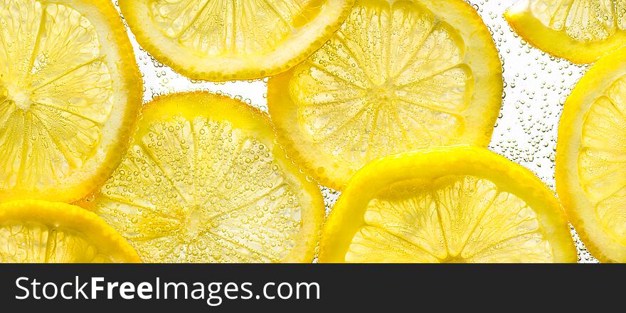 Slices of lemon in water with air bubbles on white background. Close up.