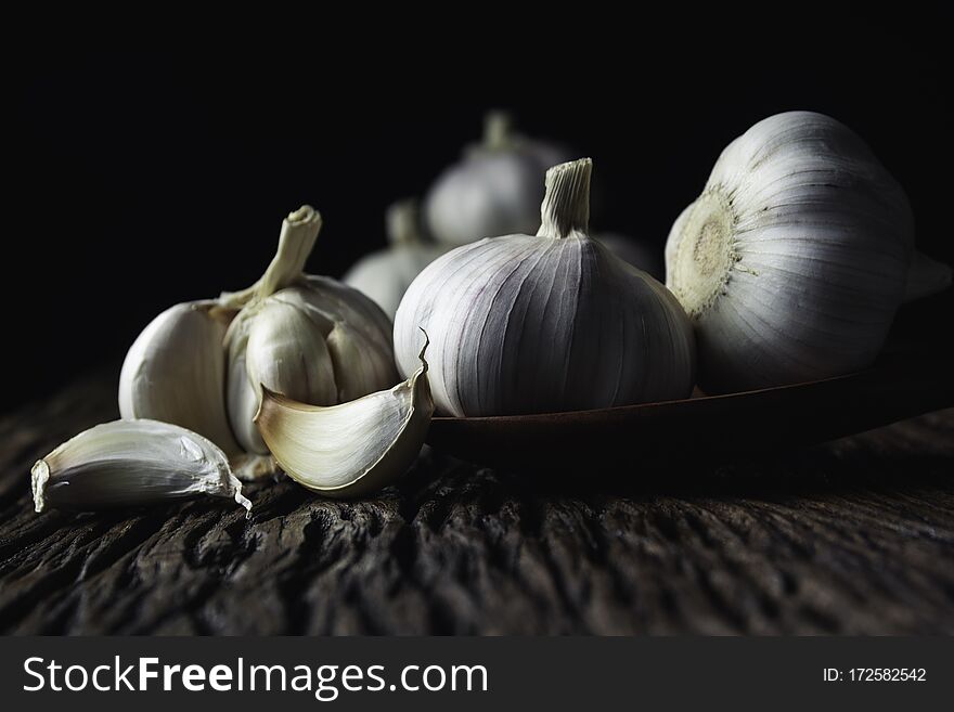 Fresh white garlic on wooden table with black background. Food and healthy concept