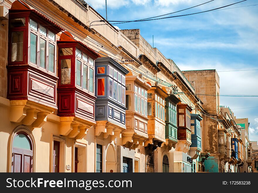 Traditional colorful maltese balconies in sunny day on old building in Valletta, capital of Malta. Travel tourist destination.