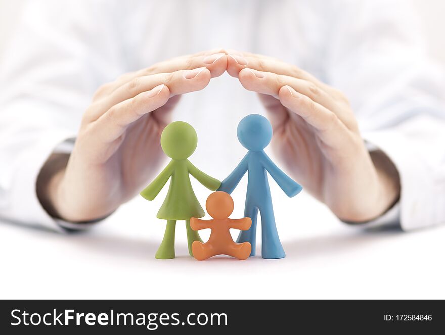 Family insurance concept with small colorful family figurines covered by hands