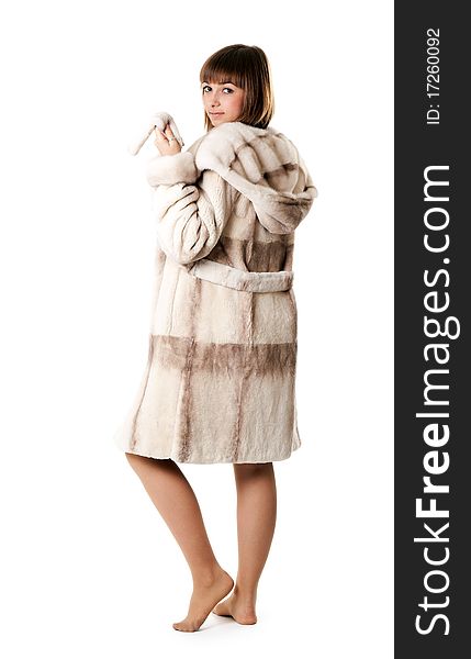 A beautiful young girl in a fur coat on a white background