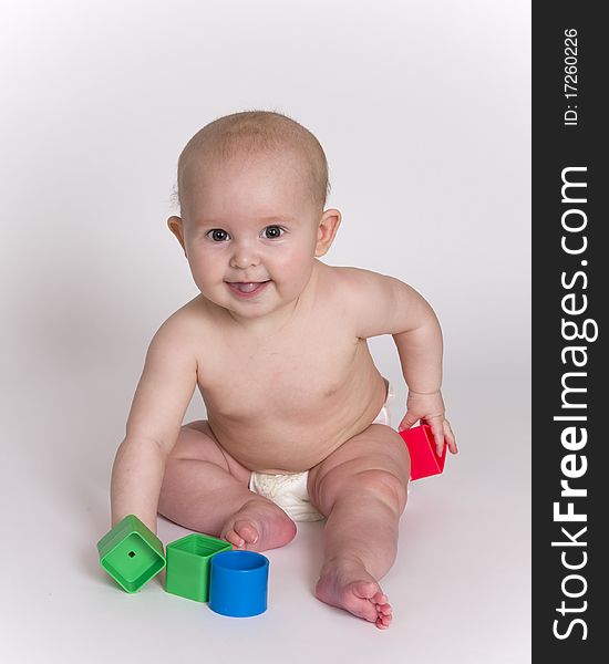Smiling bare baby sits and plays with colorful blocks. Smiling bare baby sits and plays with colorful blocks.